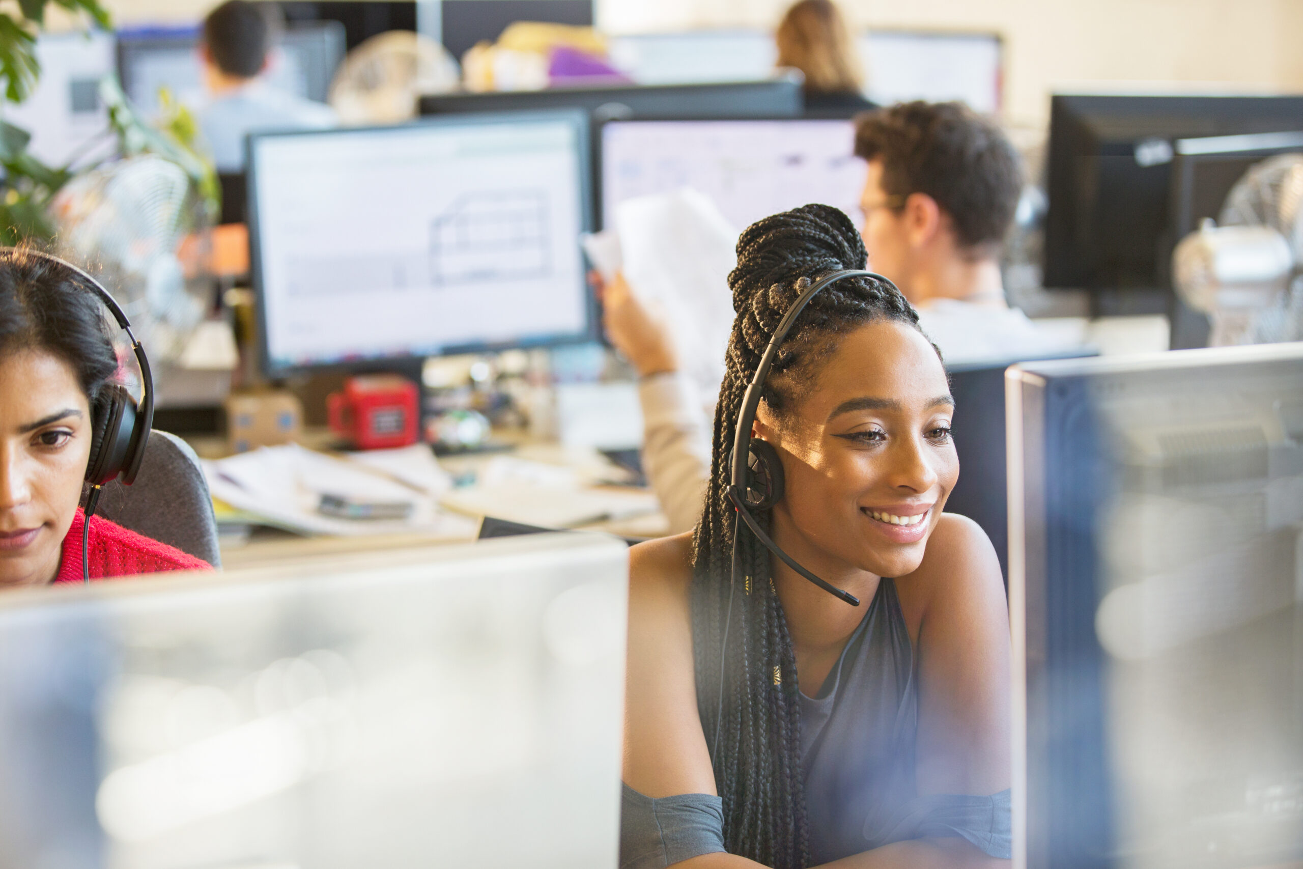 Smiling businesswoman with headset working at computer in office