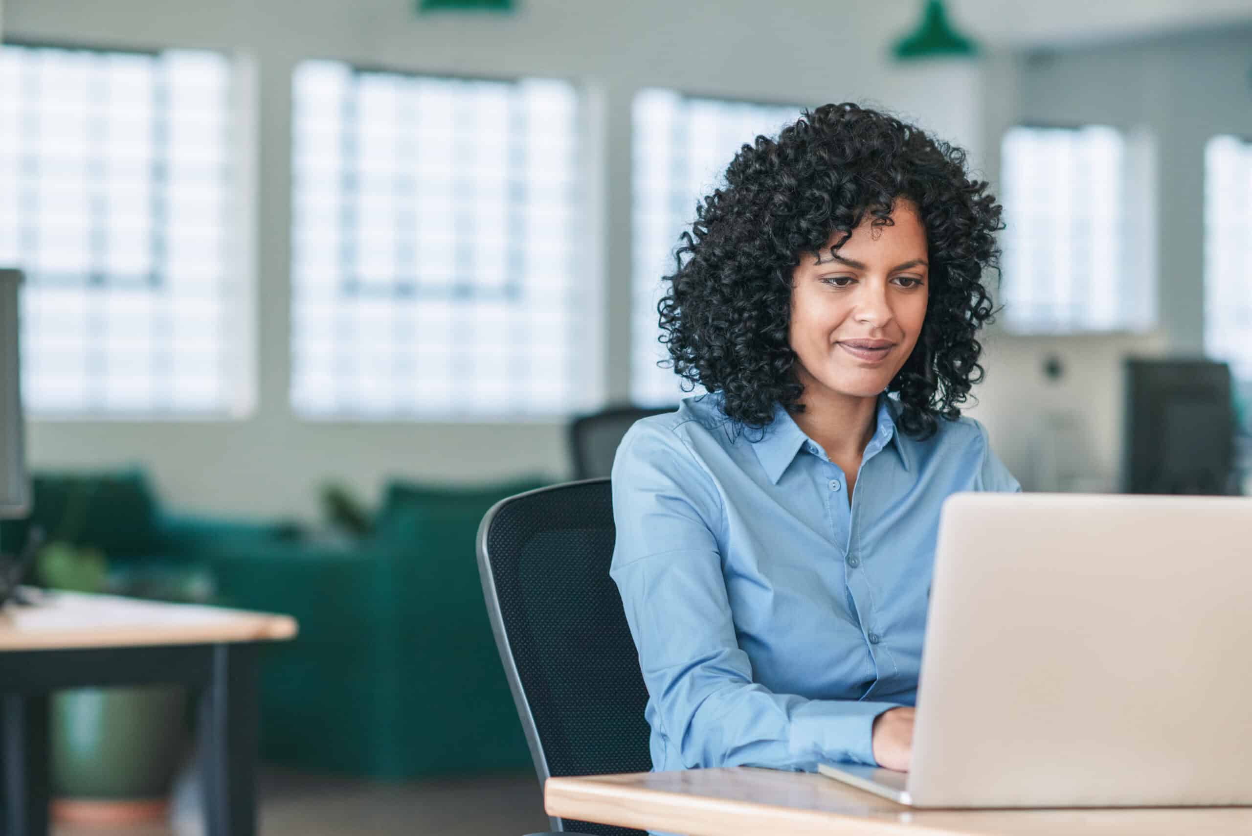 Smiling businesswoman sitting at her desk working on a laptop